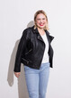 © Screen moment/Stocksy - Beautiful blonde plus size woman in jeans and a leather jacket laughs on a white background