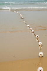 Wall Mural - white buoys on a rope stretch from the shore to the ocean