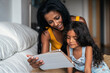 © Santi Nunez/Stocksy - Mother and daughter using device at home
