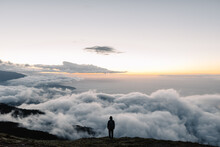 Anonymous Person Stand On The Edge Of Cliff Through The Clouds At Dawn