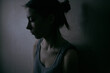 © Demetr White/Stocksy - profile portrait of a sad girl with gathered hair in the dark