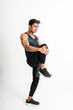 © Odua Images - full body image of muscle man wearing sportswear stands facing side do leg stretch by lifting the leg up in front of the stomach on an isolated background