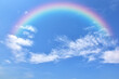 © masterjew - Abstract rainbow on beautiful blue sky and white clouds as background and wallpaper.