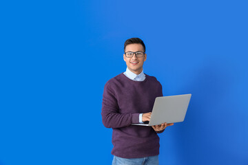 Male programmer with laptop on color background