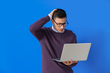 Stressed programmer with laptop on color background