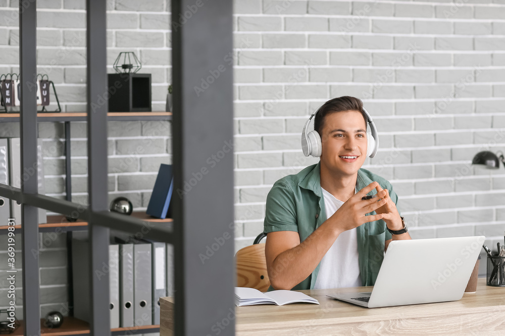Man with headphones and laptop working in office