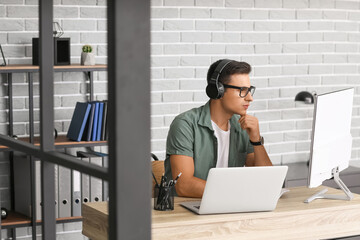 Man with headphones and computer working in office