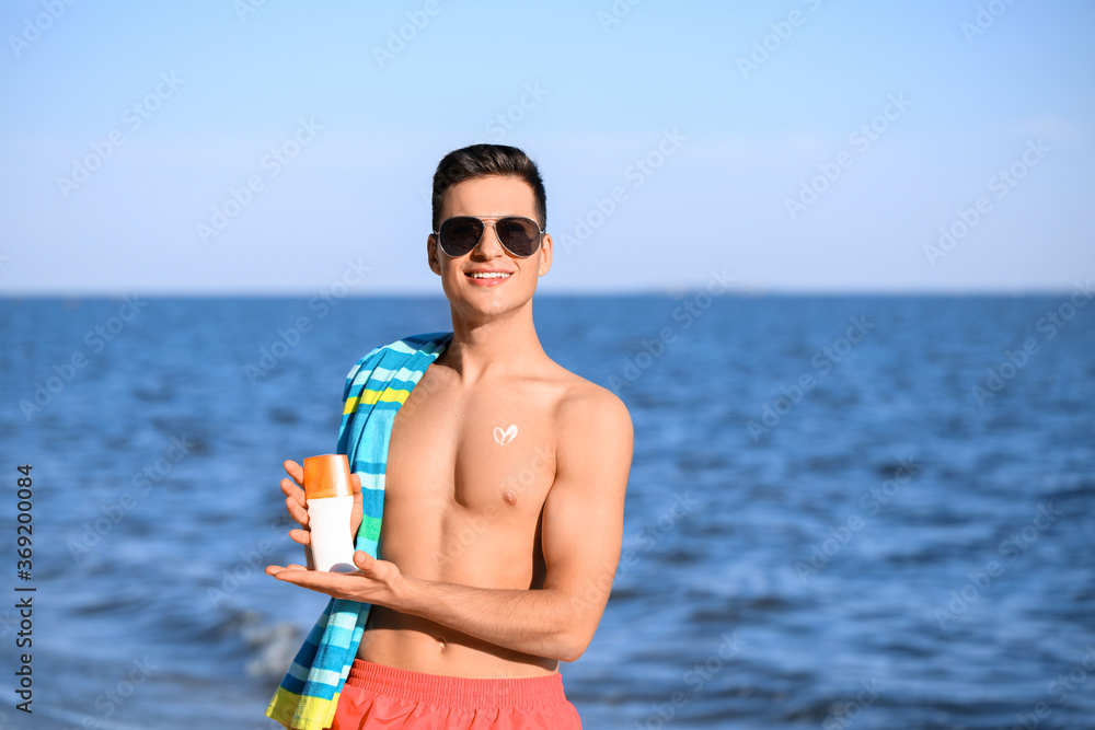 Handsome young man with sunscreen cream on sea beach