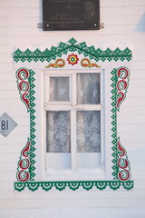 Richly decorated ornamental carved window and frame on vintage wooden rural house in village in Ulyanovsk region, Russia. Russian traditional national folk style in wooden architecture. Countryside