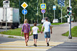 Woman, man and child cross road at crosswalk