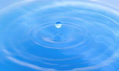  water droplets fall down closely into the blue water, making it the perfect center in nature.
