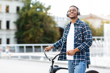 Wall Mural - Portrait of black guy standing with his bike wearing headset