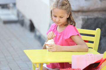 Canvas Print - beautiful girl in a pink t-shirt sits at a yellow table and eats ice cream