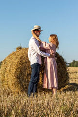 Outdoor portrait of happy couple in love on hay bale background.