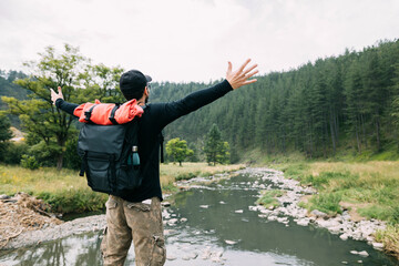 Wall Mural - Young male nature explorer enjoying the view of the river in wilderness