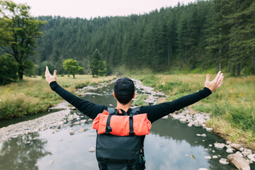 Wall Mural - Young male nature explorer enjoying the view of the river in wilderness