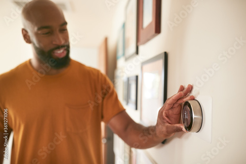 Man Adjusting Digital Central Heating Thermostat At Home Poster Mural XXL