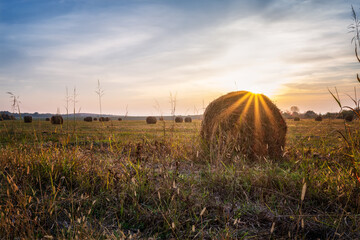 Wall Mural - amazing view with an autumn field full of hay bales and sun beams before sunset