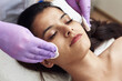 © etonastenka - Young pretty woman getting treatments in beauty salons. Young beautiful dark-haired woman lies in the beautician's office and makes face peeling. Cleansing the skin with cotton pads