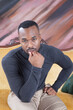 © Allen Penton - Pensive handsome black man sitting on a couch