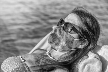 Canvas Print - Woman wearing mask lying on the beach in covid times