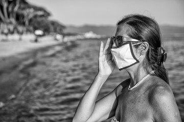 Sticker - Woman walking on the beach wearing mask in coronavirus times