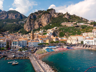 Wall Mural - Aerial view from the sea of the Amalfi Coast with Amalfi city, Summer day. Travel and vacation to Europe mountains. Boats and ships, the most popular beach. Breakwater. Houses and hotels. Italy