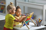 children of different races sit together at the table and count on the abacus