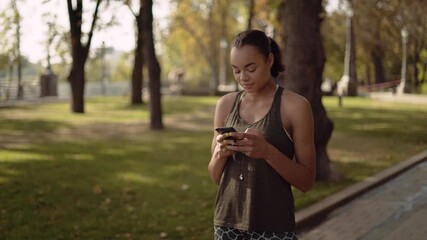 Beautiful exotic mixed race girl sends messages using a selfie. sports girl in the park. 4K