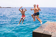 © Daniel - group of friends jumping off together at the beach doing flips and having fun in the water - people enjoyinng thei holiday at the beach playing and laughing - looking at the camera while jumping