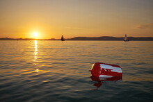 Golden Sunset Over Lake Balaton With Sailboats And A Red Buoy In The Foreground