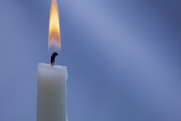 Burning white candle on a purple-purple background