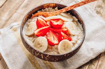 Poster - Quinoa porridge with coconut milk and fresh strawberries in a coconut bowl wooden rustic background. Healthy Lactose and Gluten Free Breakfast.