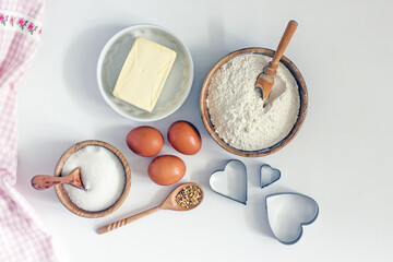 Ingredients for home baking cookies butter, sugar, eggs, flour, cookie cutters, rolling pin on a light background, top view. DIY homemade cookies background