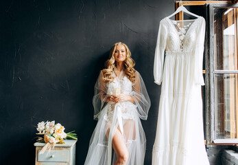 Bride`s morning. Beautiful young woman in white robe holding champagne glass in hand.