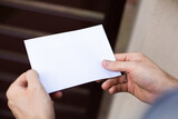 Fototapeta Kwiaty - Male hands holding a letter, close up, focus on letter. Envelope with a copy-space.
