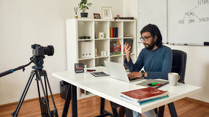 Recording video tutorial about HTML. Professional male computer programming teacher looking at camera and talking while giving online lesson