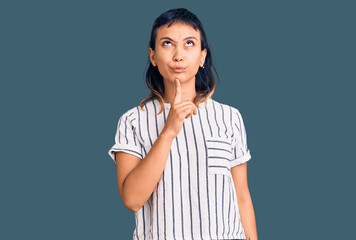 Young woman wearing casual clothes thinking concentrated about doubt with finger on chin and looking up wondering