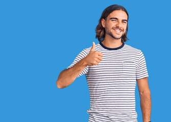 Young handsome man wearing casual clothes doing happy thumbs up gesture with hand. approving expression looking at the camera showing success.