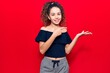 © Krakenimages.com - Beautiful kid girl with curly hair wearing casual clothes amazed and smiling to the camera while presenting with hand and pointing with finger.