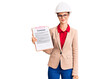© Krakenimages.com - Young beautiful woman wearing architect hardhat holding clipboard with contract document looking positive and happy standing and smiling with a confident smile showing teeth