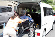 女性介護スタッフの支援で車椅子のまま福祉車両に乗り込む男性高齢者