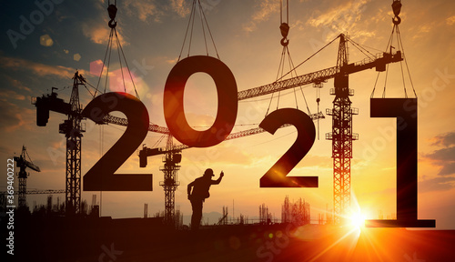 Fotografía Cranes building construction 2021 year sign,Silhouette staff works as a team to