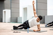 © Atstock Productions - Athletic Indian man doing side plank exercise outdoors on rooftop with friends
