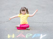 © Ermolaev Alexandr - Little girl with syndrome down draws word 'happy' with chalk on the asphalt