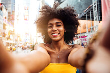 Portrait Of Happy Young Woman With Afro Hairstyle Taking Selfie On City Street