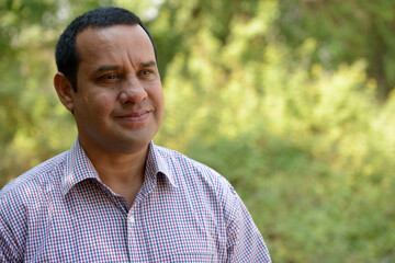 Portrait of overweight Indian businessman at the park outdoors