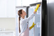 © New Africa - Woman in rubber gloves cleaning refrigerator at home