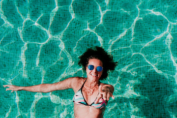 Wall Mural - top view of happy young woman floating in a pool. summer and fun lifestyle