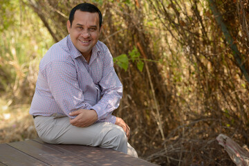 Portrait of happy overweight Indian businessman at the park outdoors